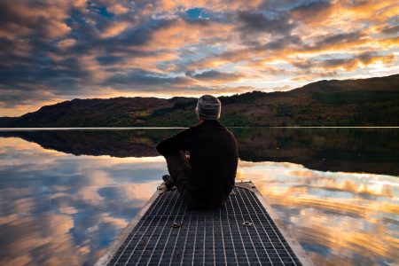 Man Sitting By Lake Free Stock Photo