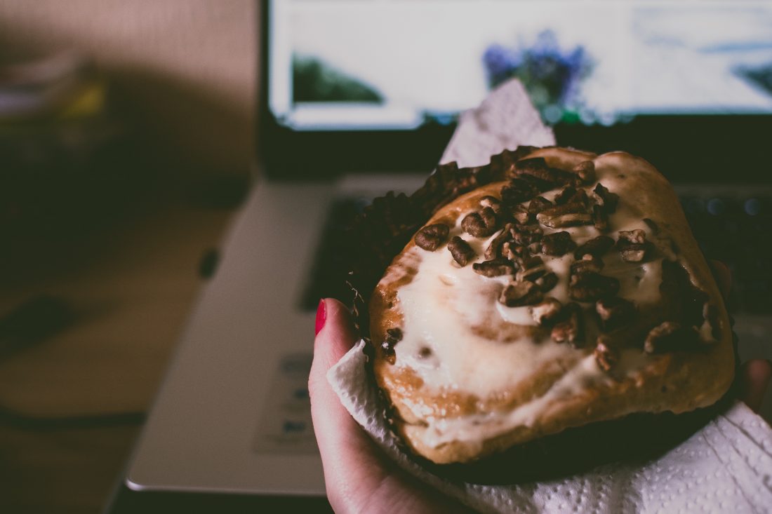 Free photo of Eating Muffin on Laptop