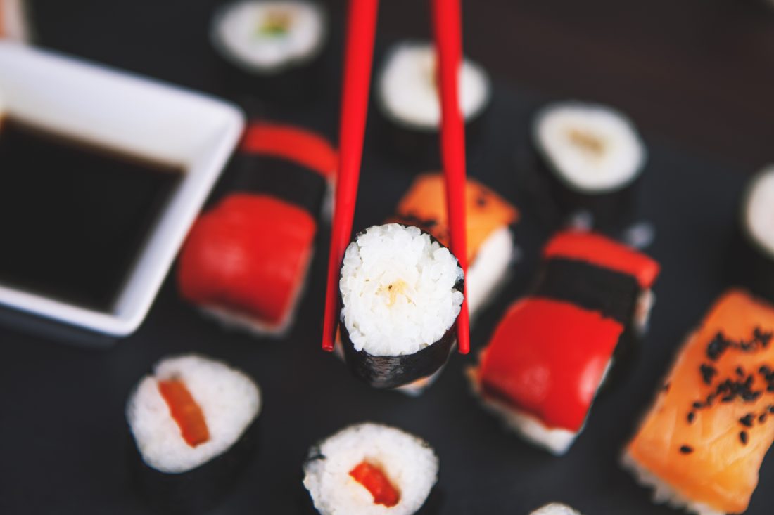 Free photo of Sushi Held in Chopsticks