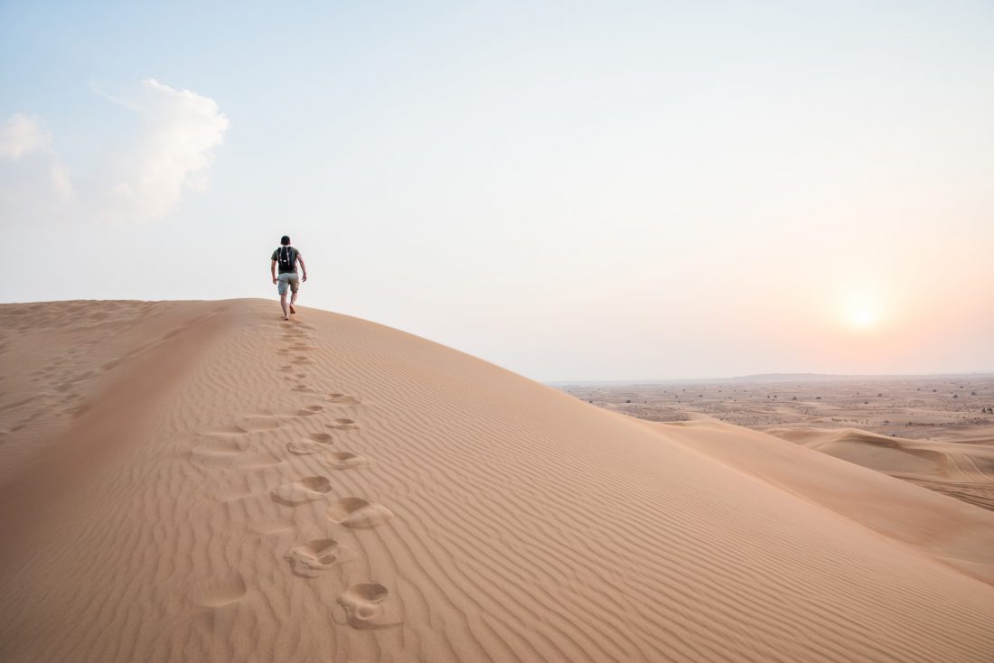 Free photo of Man Walking Up Sand Dunes
